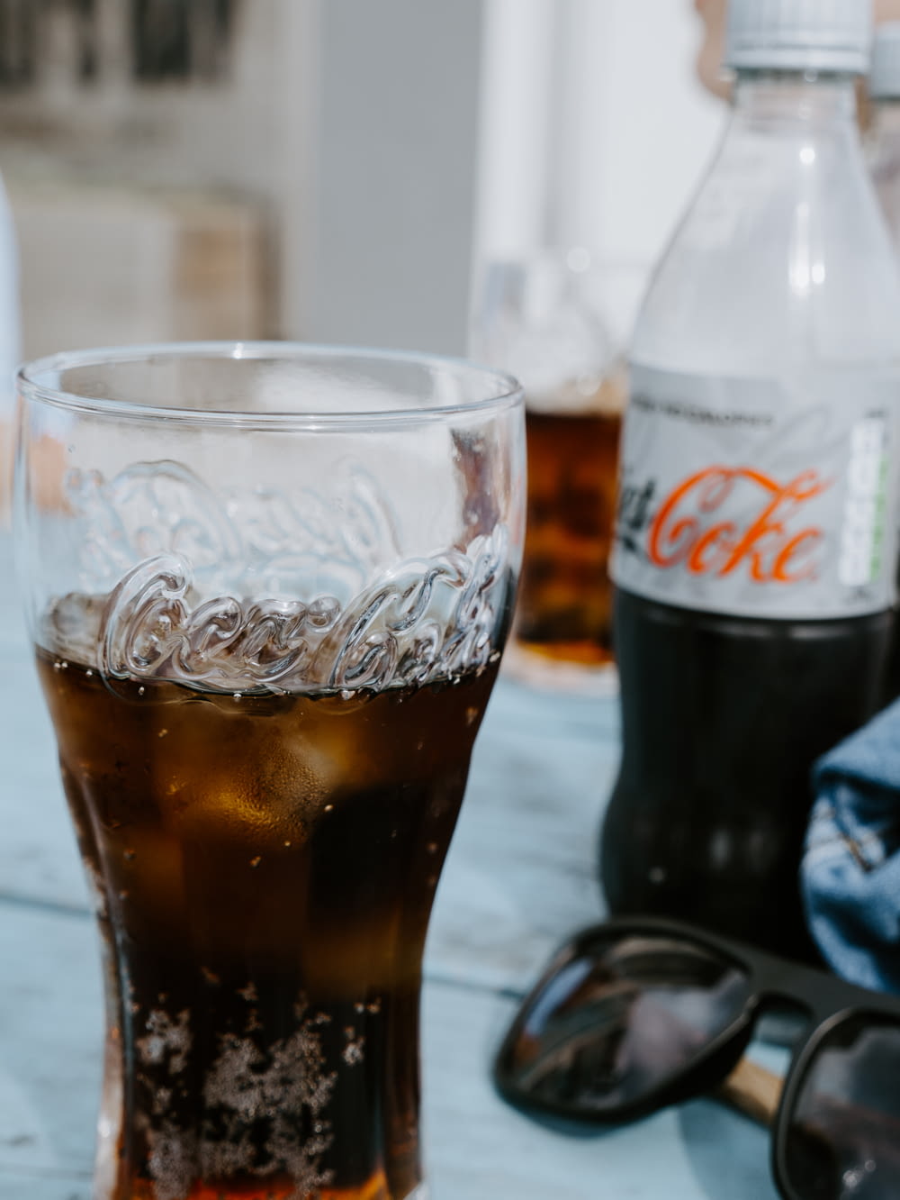 Botella de Coca Cola Light junto a un vaso transparente