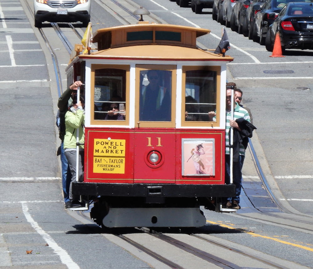 people riding red and yellow tram during daytime