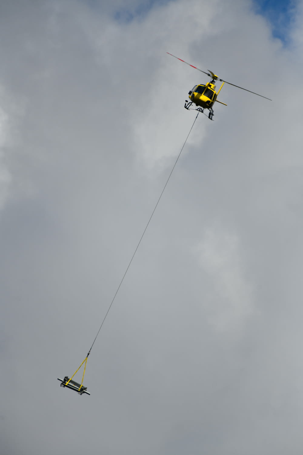 yellow and black helicopter flying under white clouds during daytime