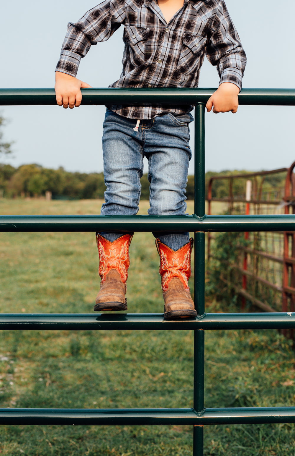 person in blue denim jeans and brown leather cowboy boots sitting on black metal railings during