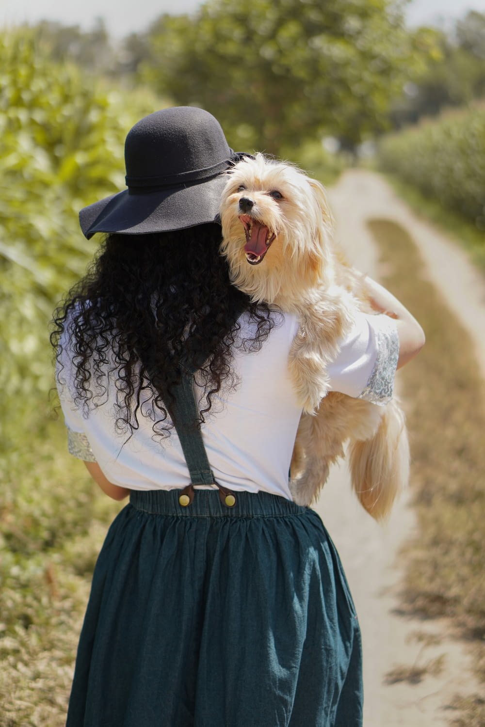 woman in black hat carrying brown long coated small dog