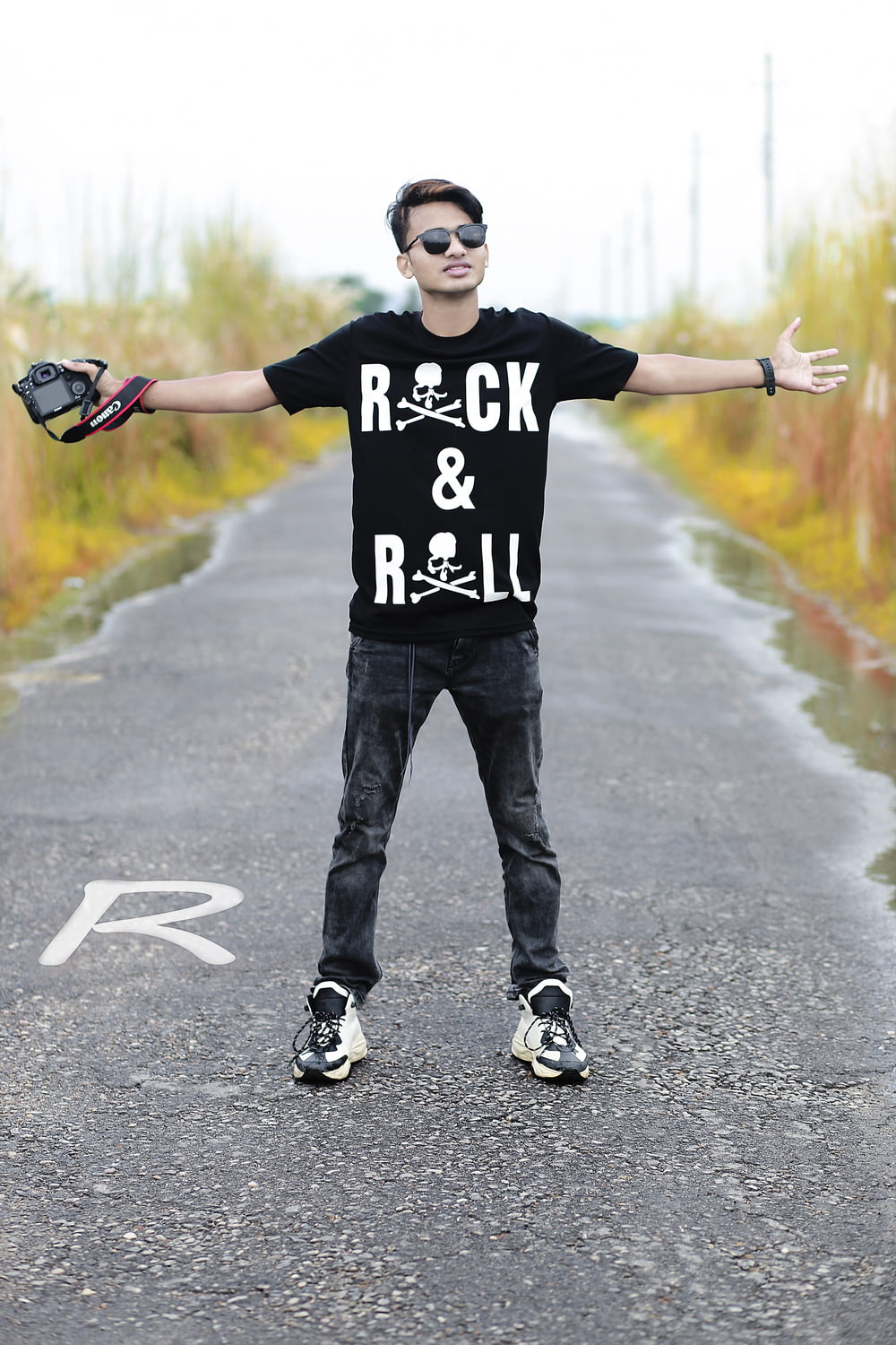 man in black and white crew neck t-shirt and black denim jeans standing on gray