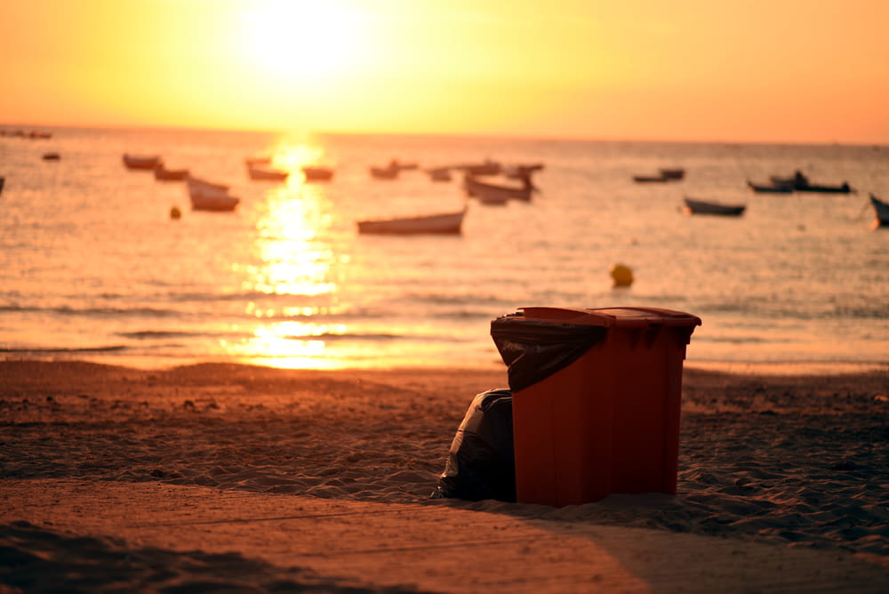 brown plastic bucket on beach shore during sunset