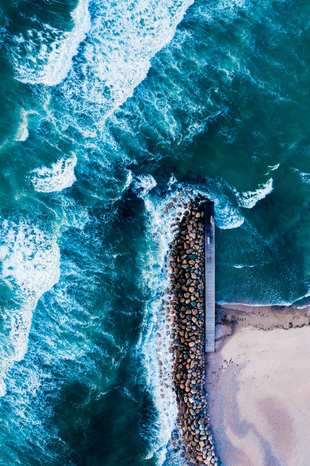 aerial view of sea waves crashing on shore during daytime