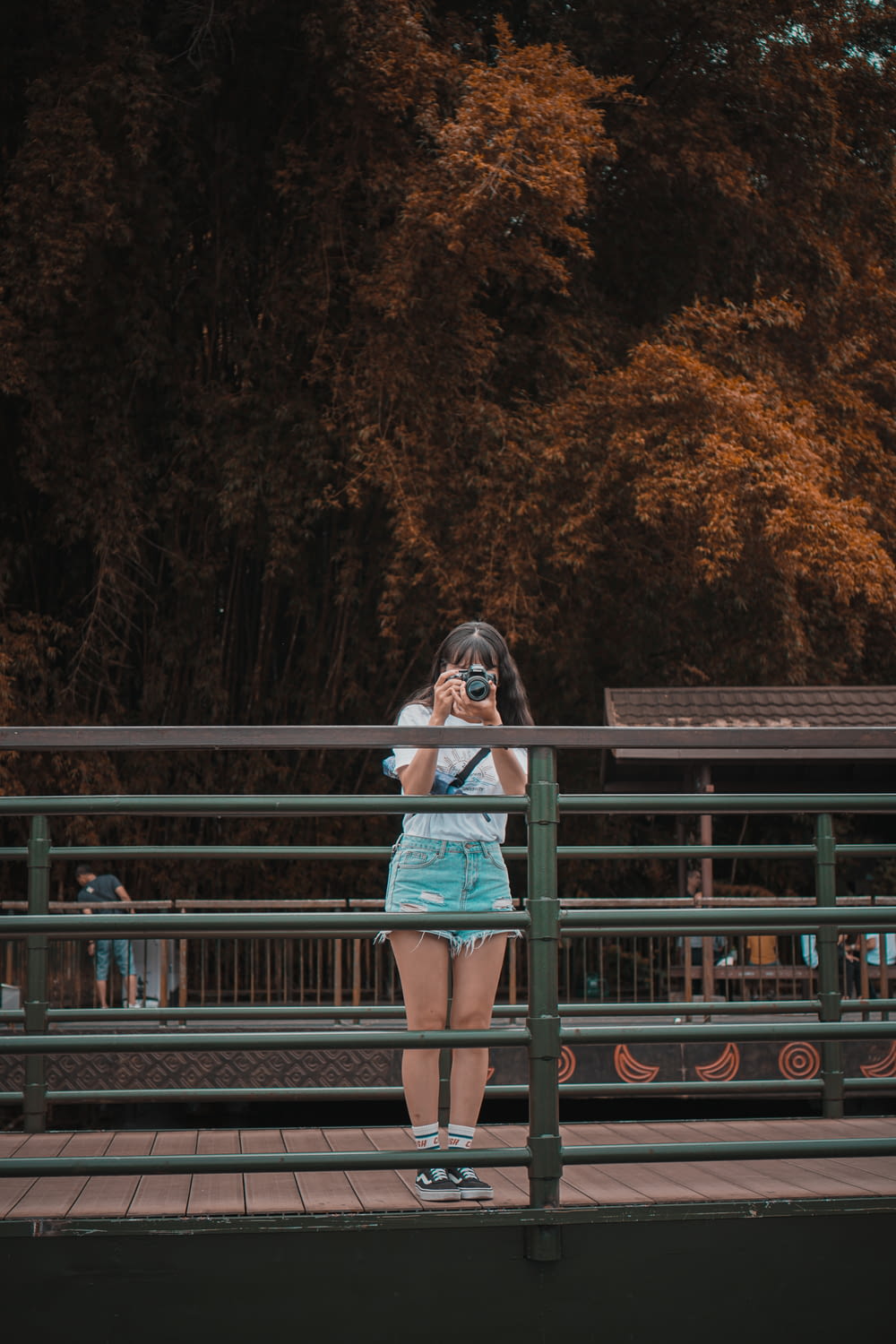 woman in teal and white dress standing on bridge