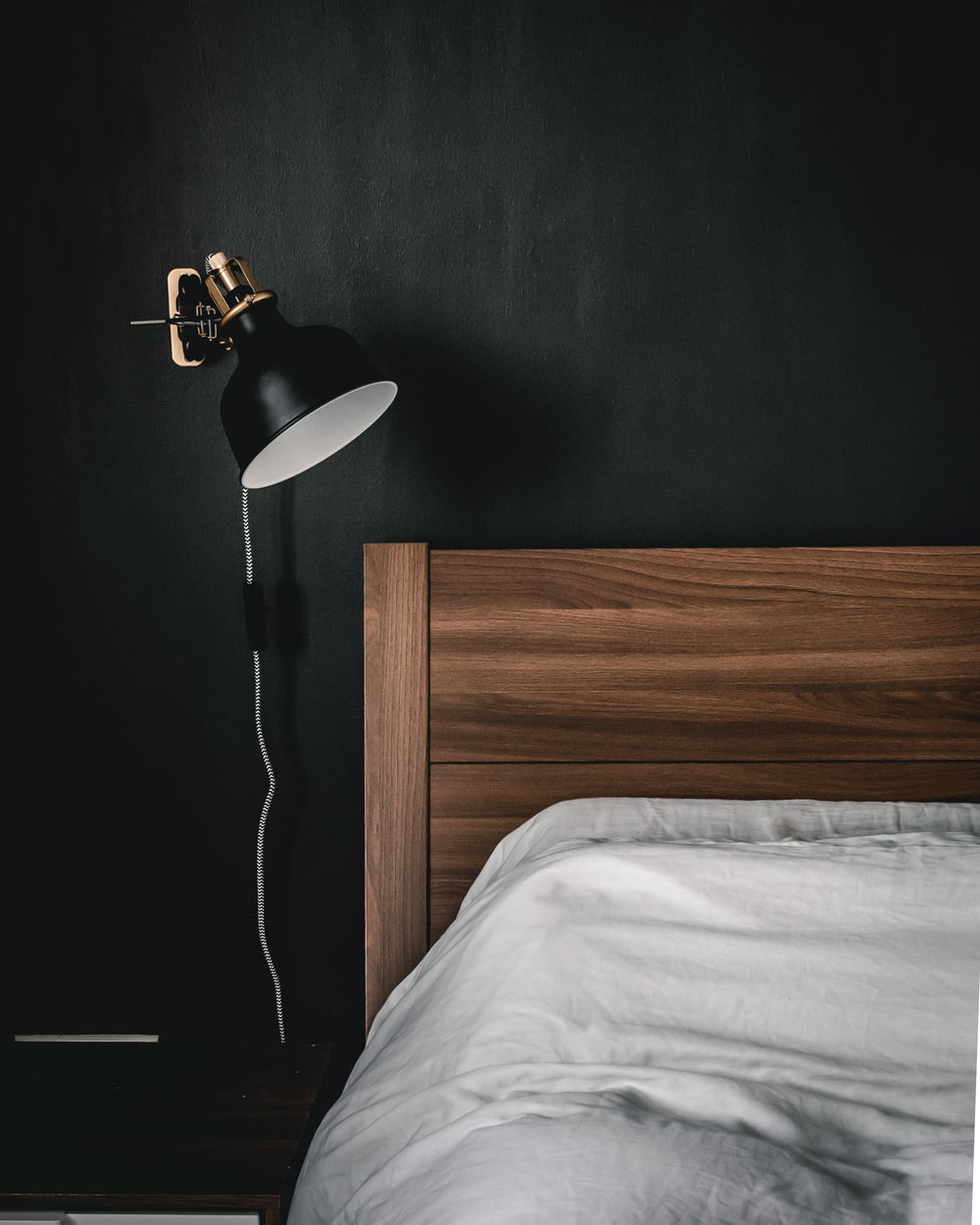 Lámpara de mesa en blanco y negro sobre mesita de noche de madera marrón