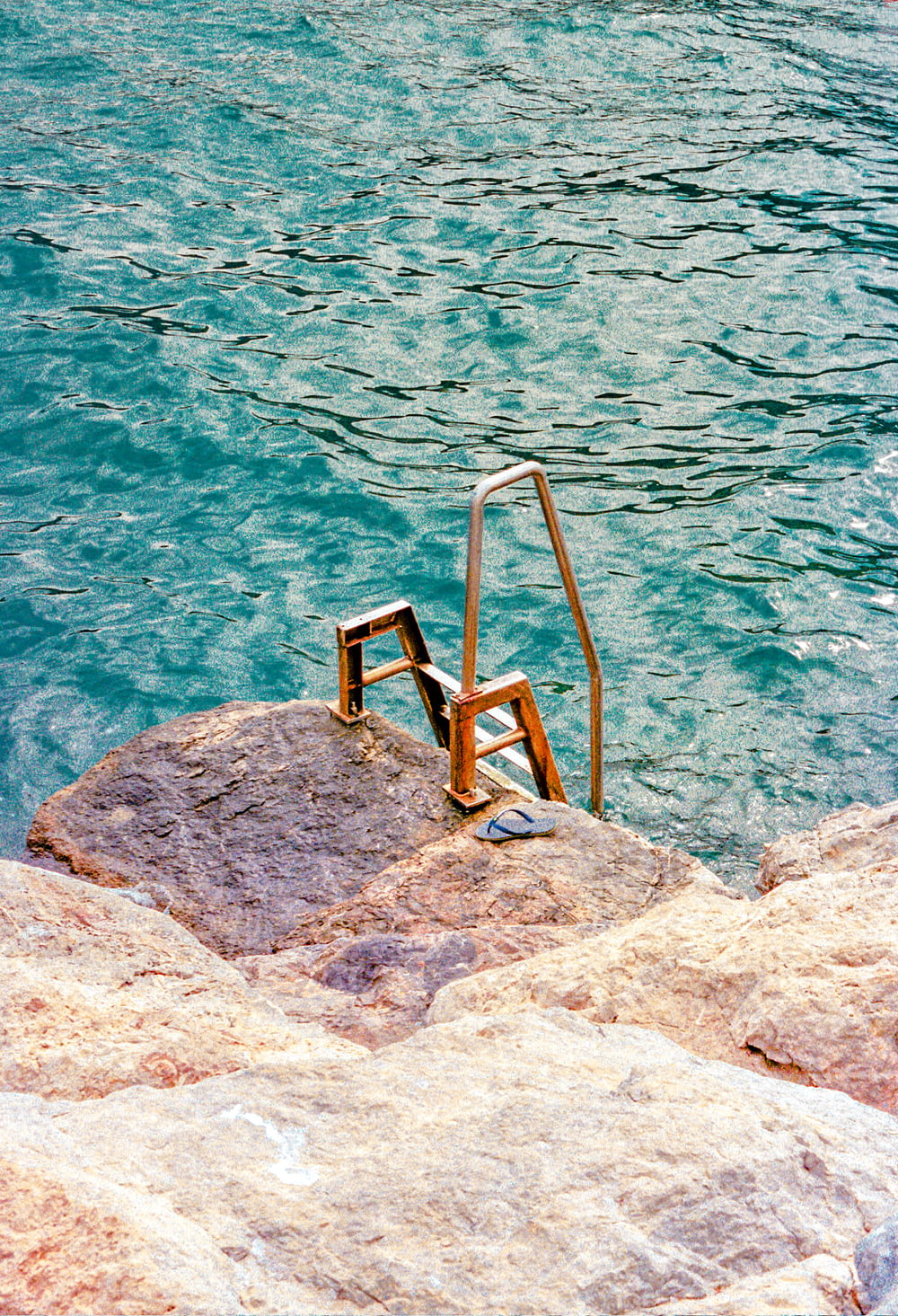escada de madeira marrom na rocha cinzenta perto do corpo de água durante o dia