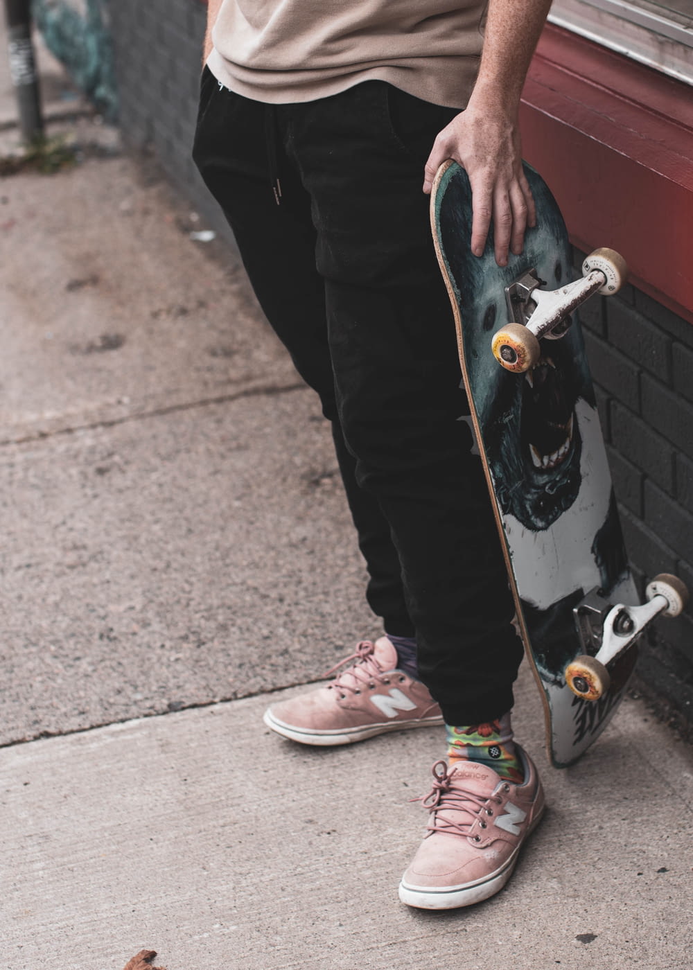 person in black pants and pink and white nike sneakers holding skateboard