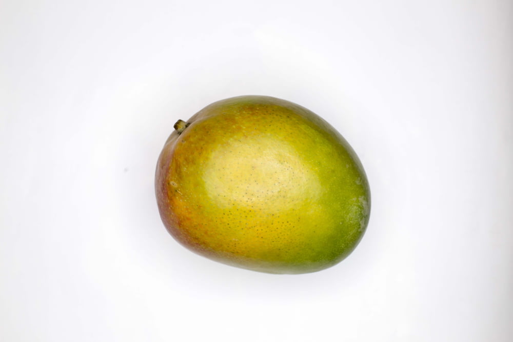 grüne runde Frucht auf weißer Oberfläche