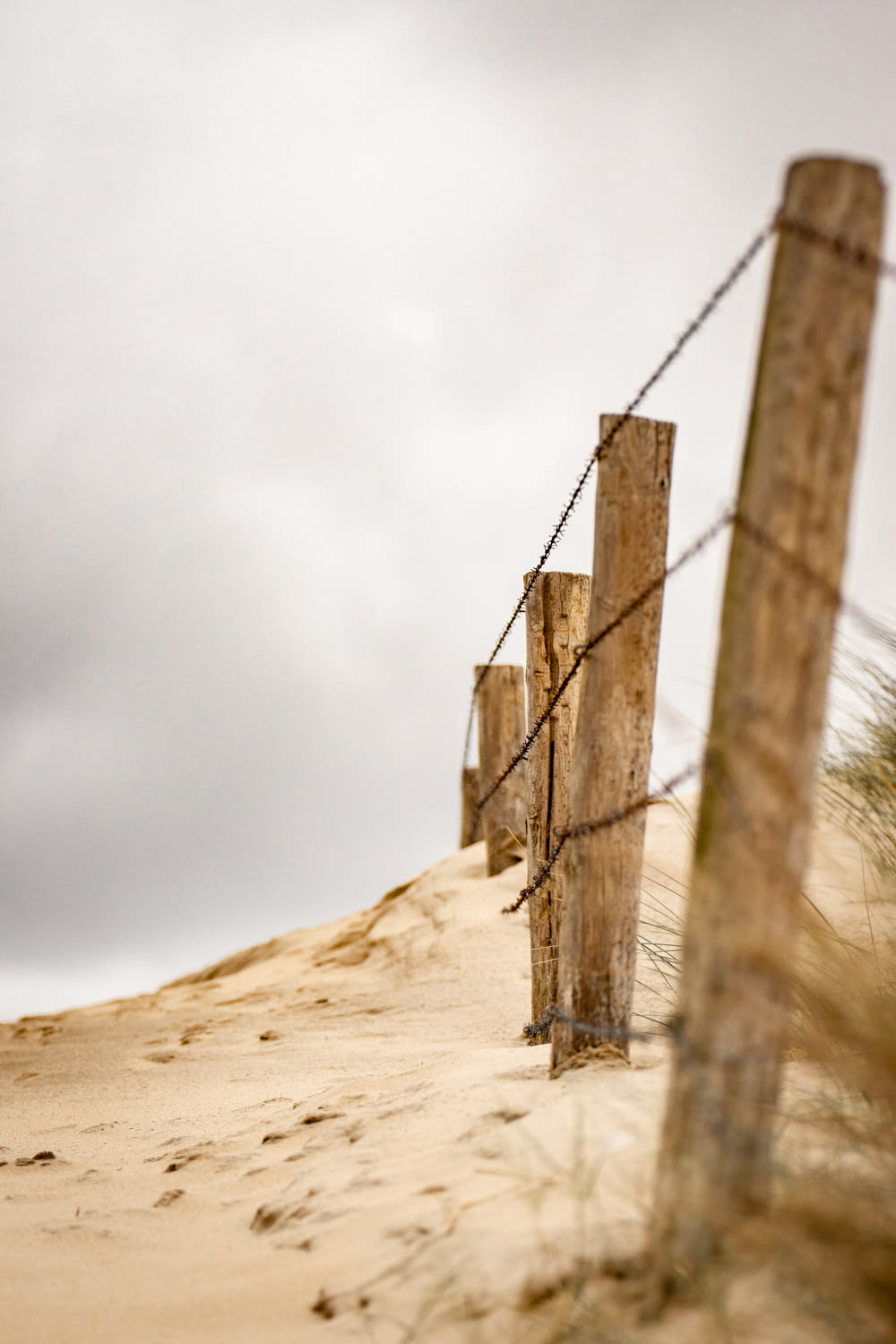 brown wooden fence on brown sand under white cloudy sky during daytime