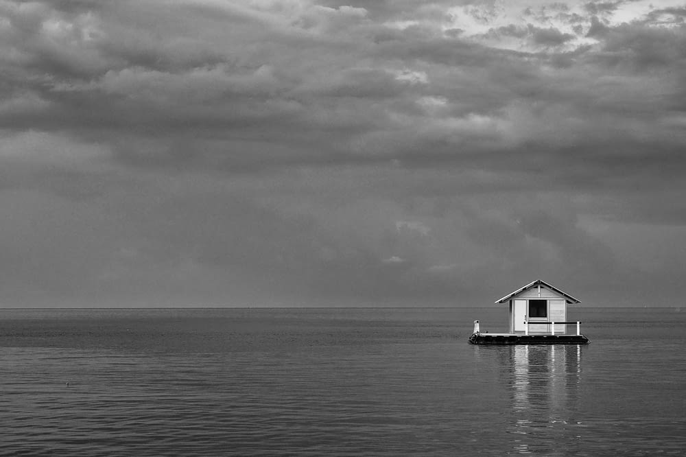 grayscale photo of house on body of water
