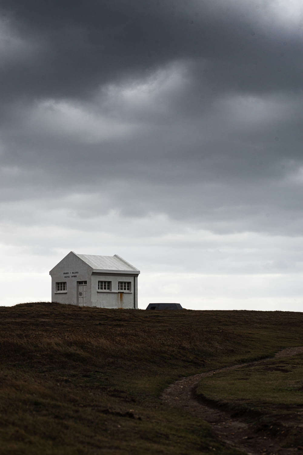 casa de madeira branca no campo de grama verde sob nuvens brancas