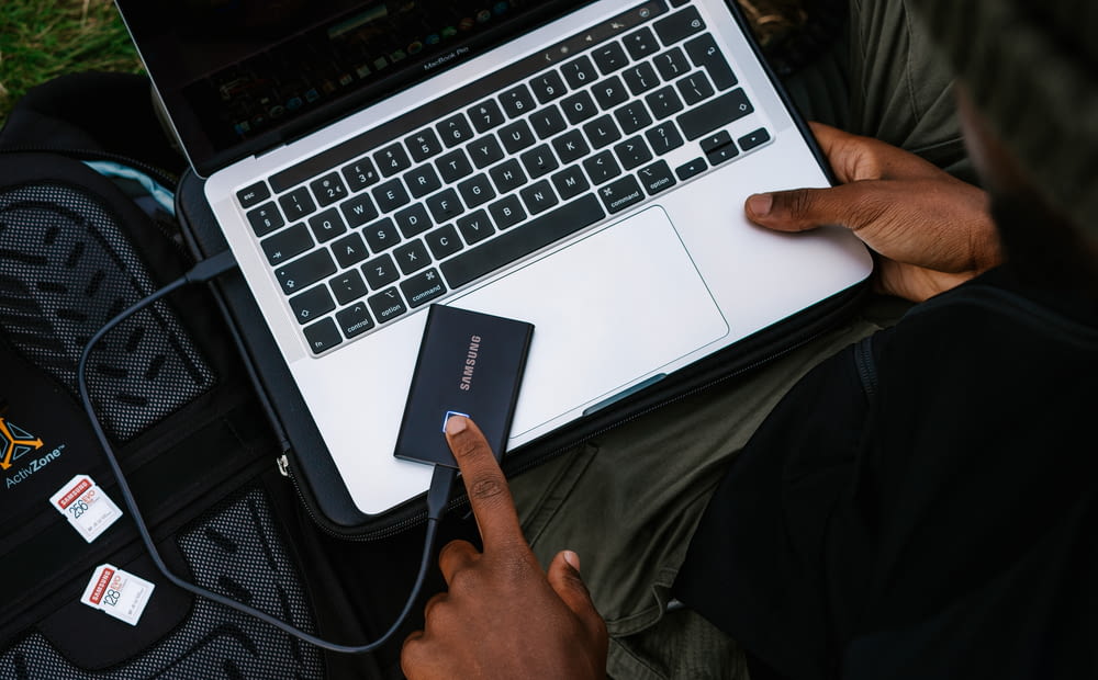 Persona sosteniendo una computadora portátil plateada y negra