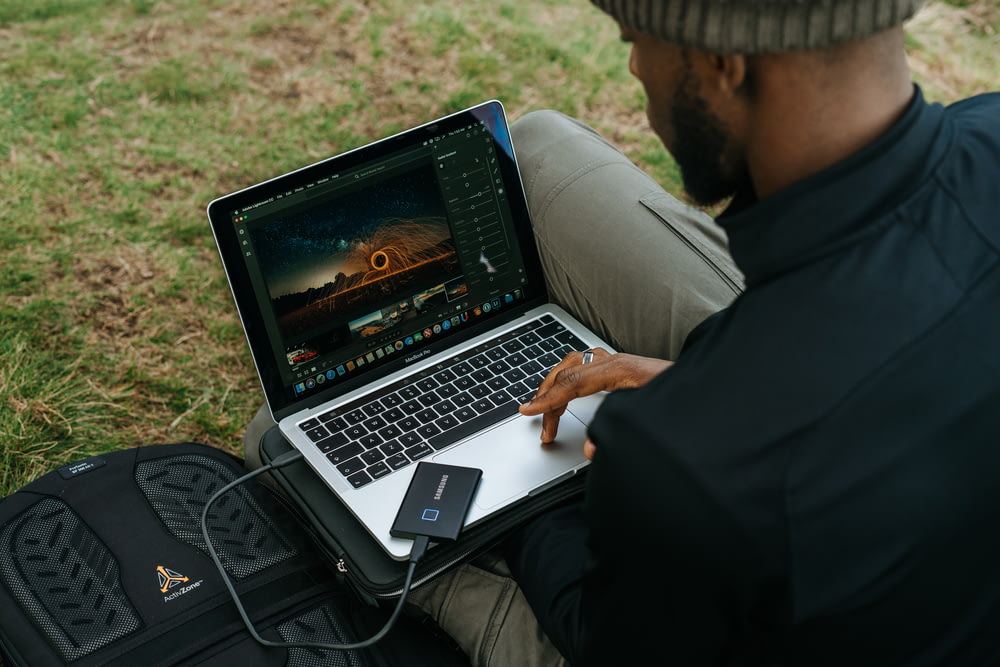 Mann in schwarzer Jacke mit MacBook Pro