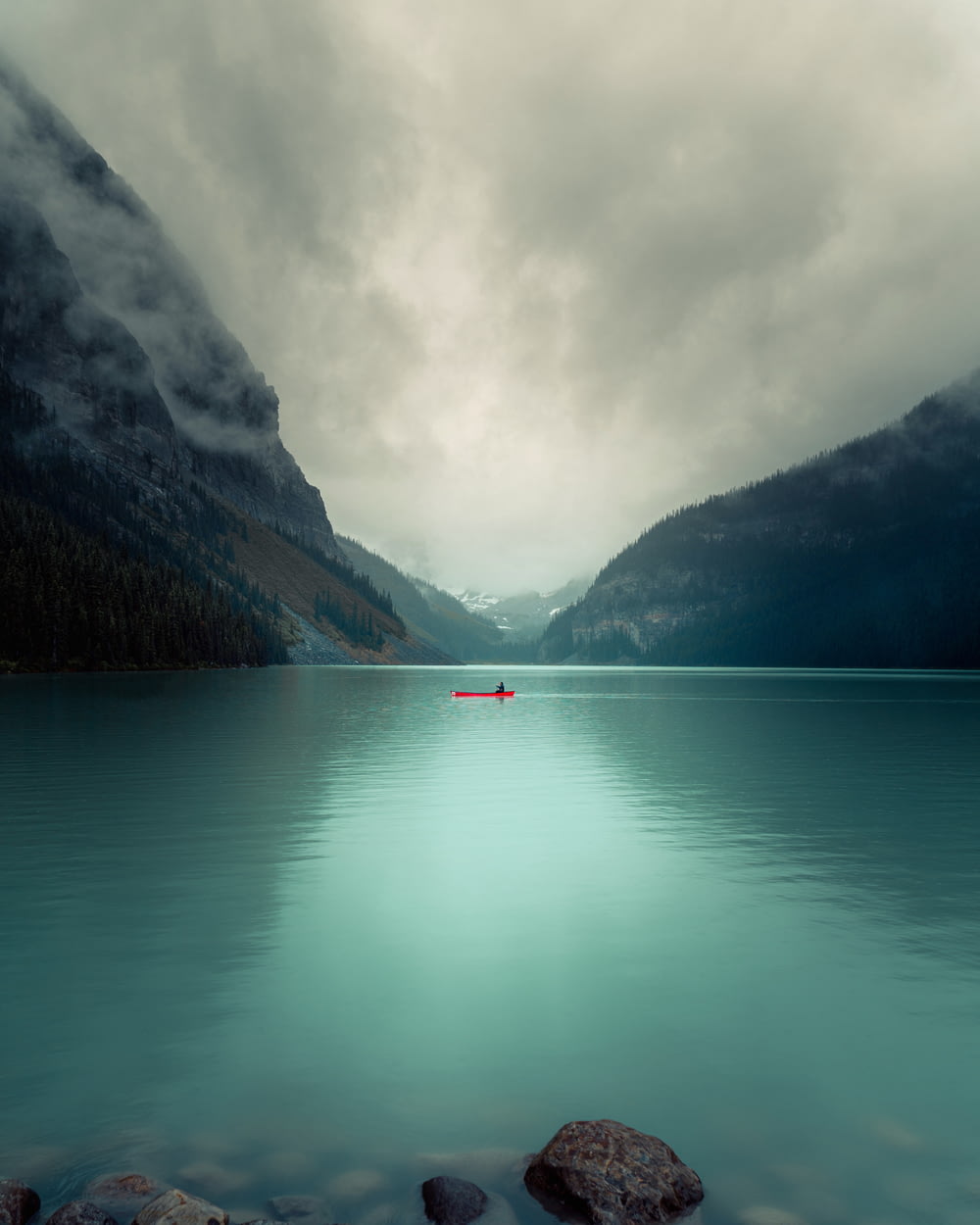 red boat on calm water near mountain during daytime