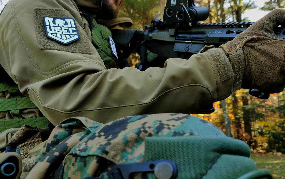 homme en uniforme de camouflage vert et marron de l’armée tenant un fusil