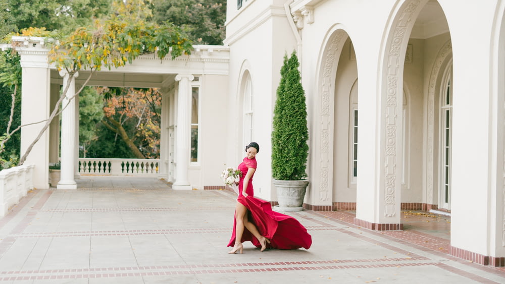 Una mujer con un vestido rojo camina frente a un edificio