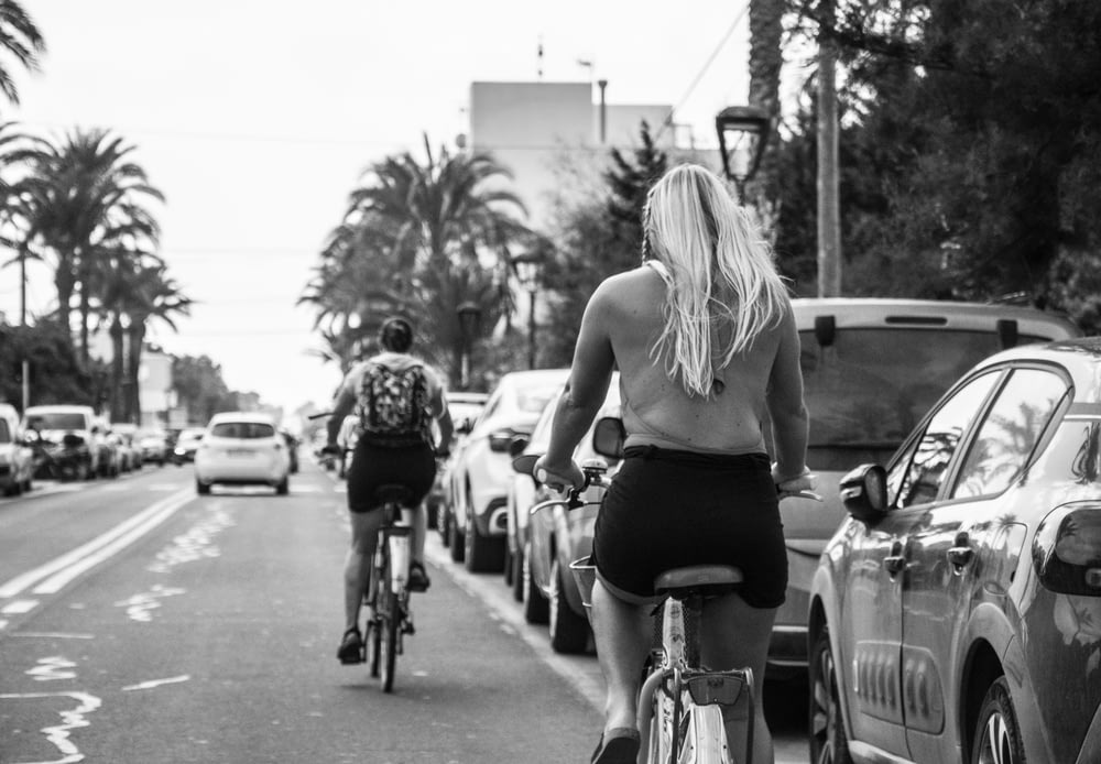 grayscale photo of woman in tank top riding on bicycle