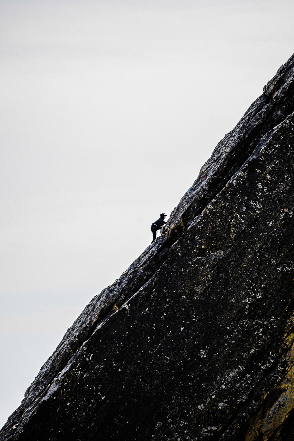 person in black jacket climbing on brown rock mountain during daytime