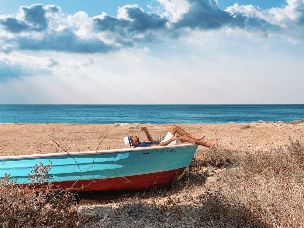red and blue boat on seashore during daytime