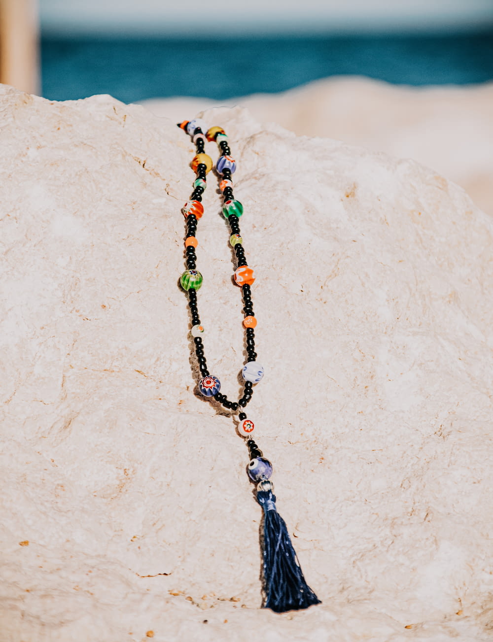 black green and yellow beaded necklace on white sand