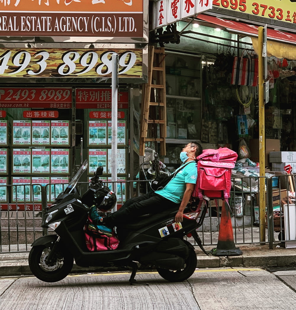 woman in pink jacket riding on black motorcycle