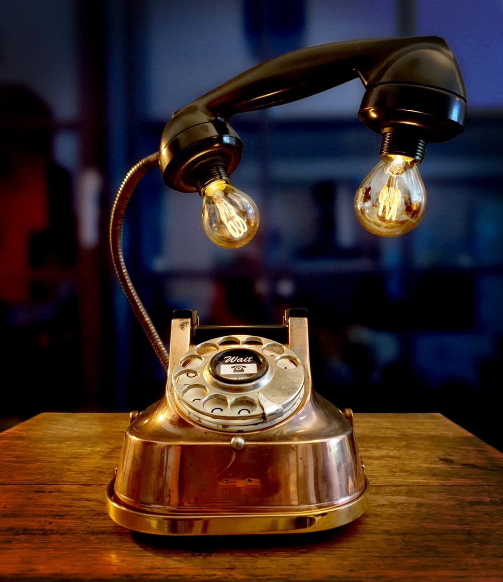 gold rotary phone on brown wooden table