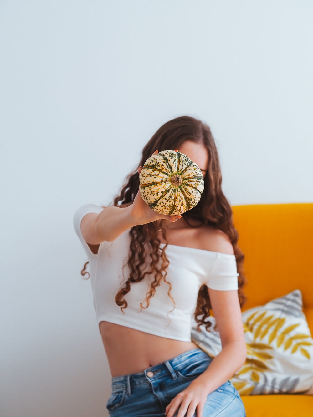 woman in white crop top and blue denim daisy dukes with brown and yellow sunflower headdress