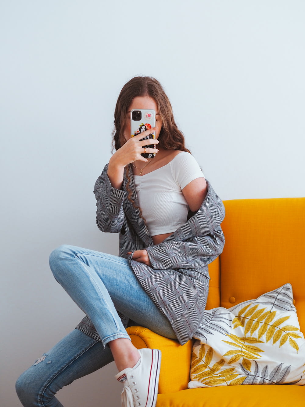 woman in gray cardigan and blue denim jeans sitting on yellow couch