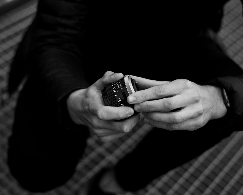 grayscale photo of person holding black and silver watch