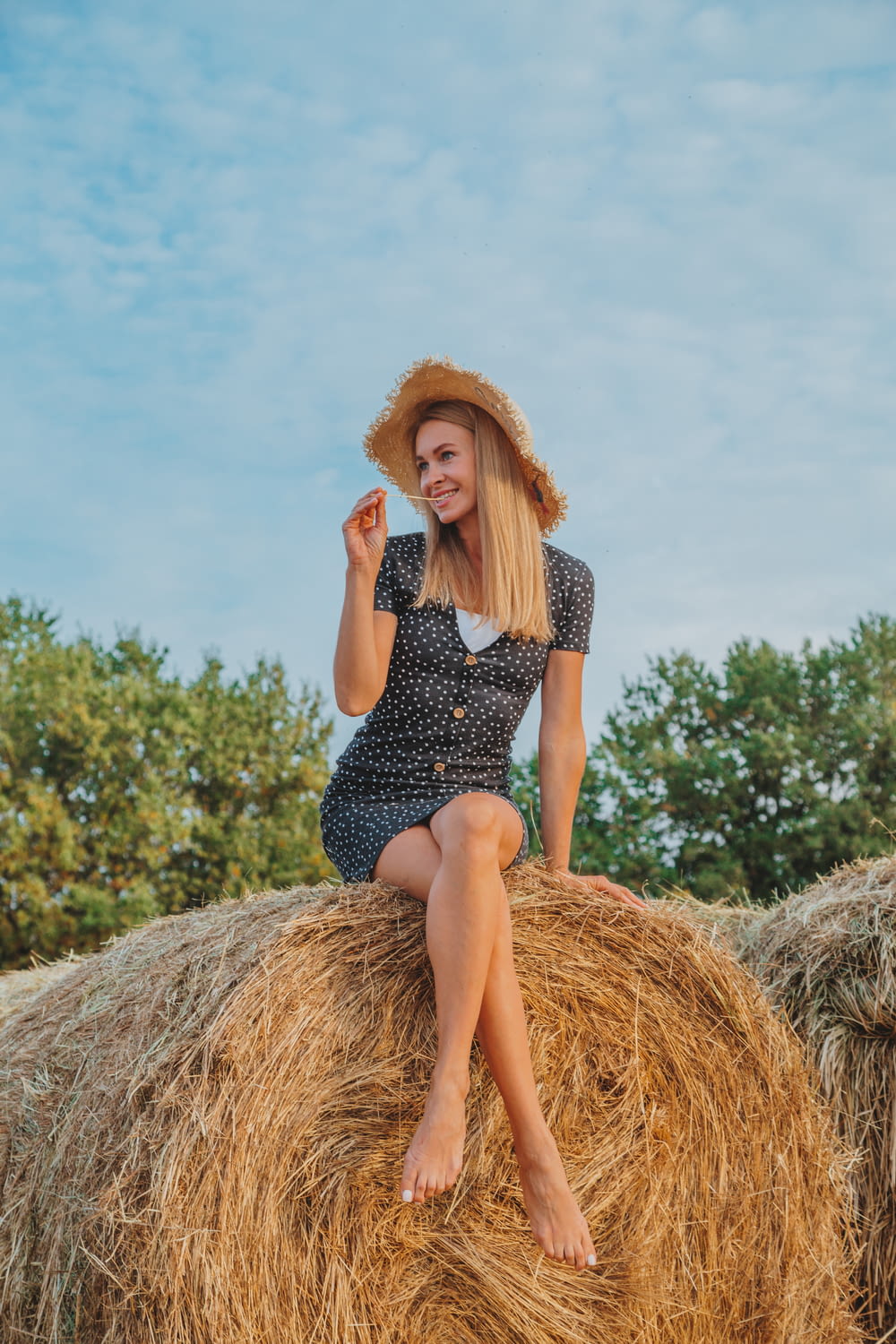 woman in black and white polka dot dress sitting on brown hay