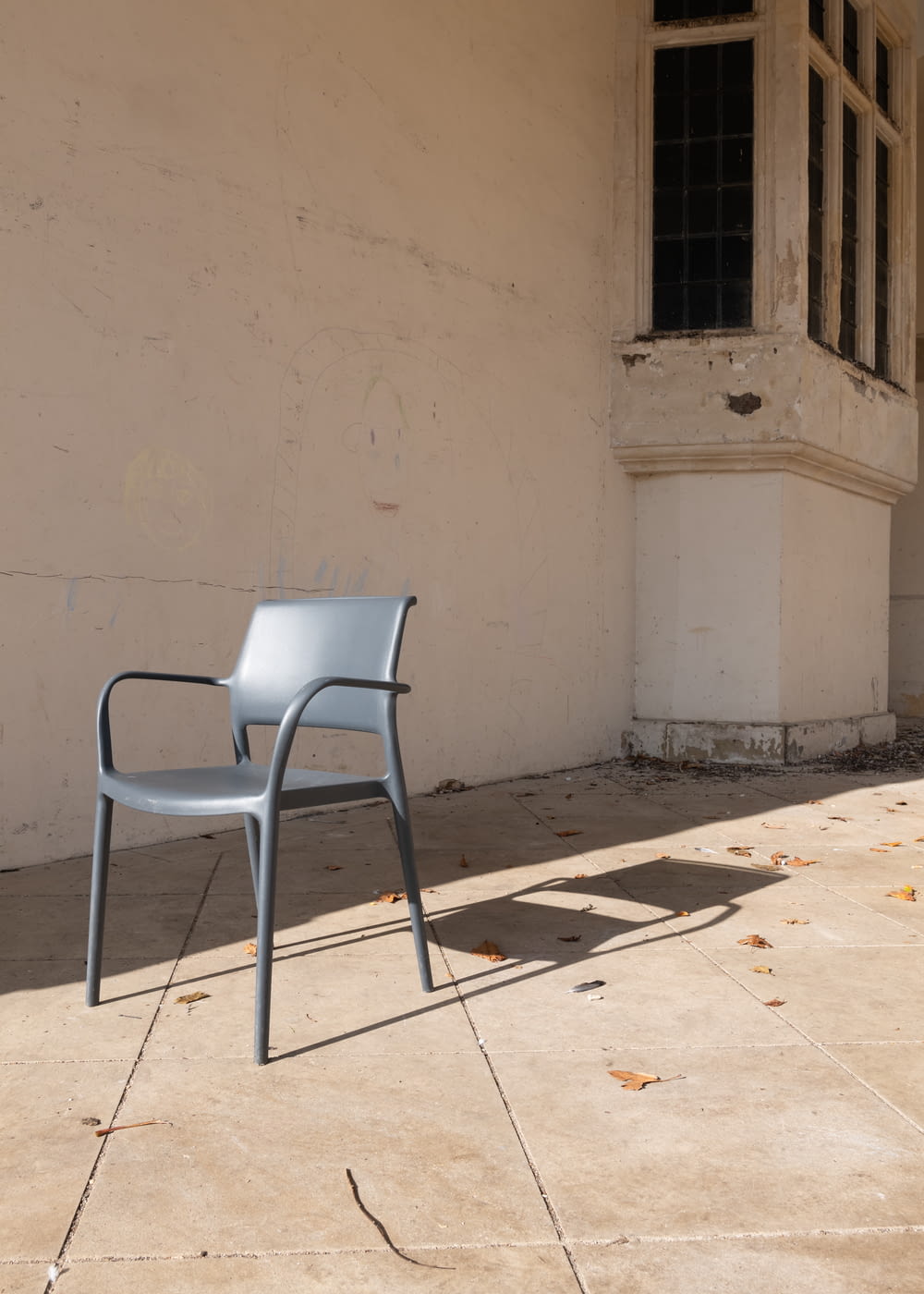 gray plastic chair beside white concrete wall