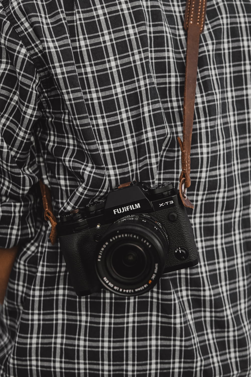 Cámara réflex Nikon negra sobre textil a cuadros blancos y negros