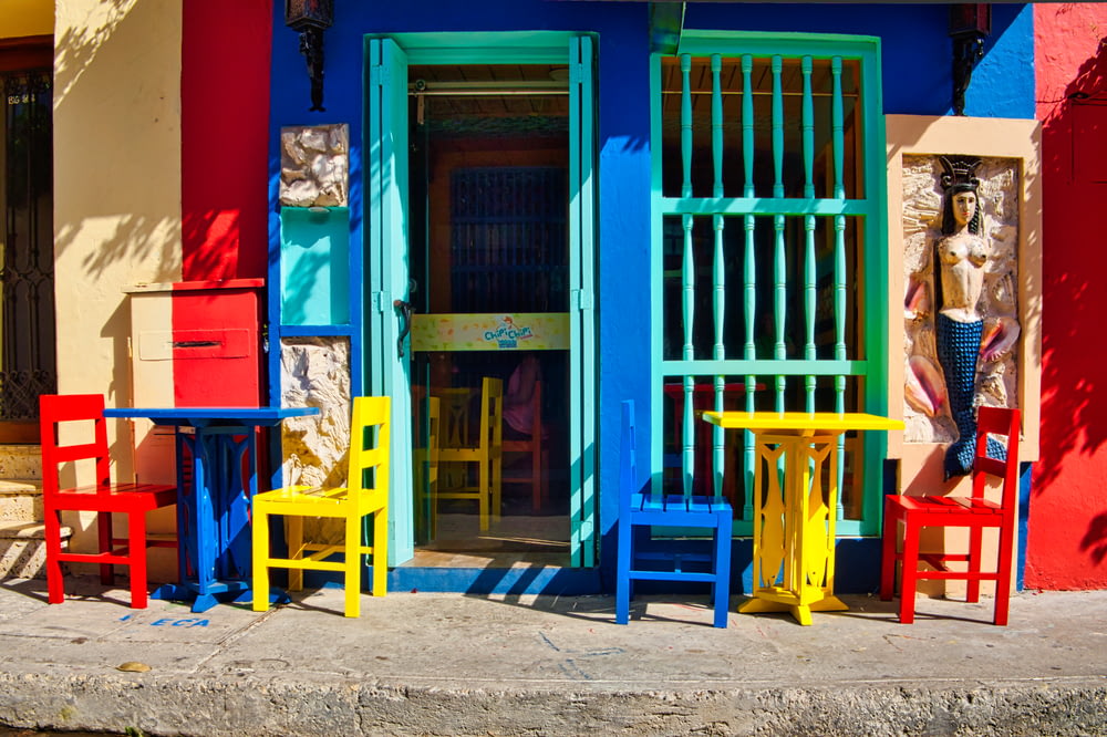 blaue Holztür mit roten und blauen Holzstühlen