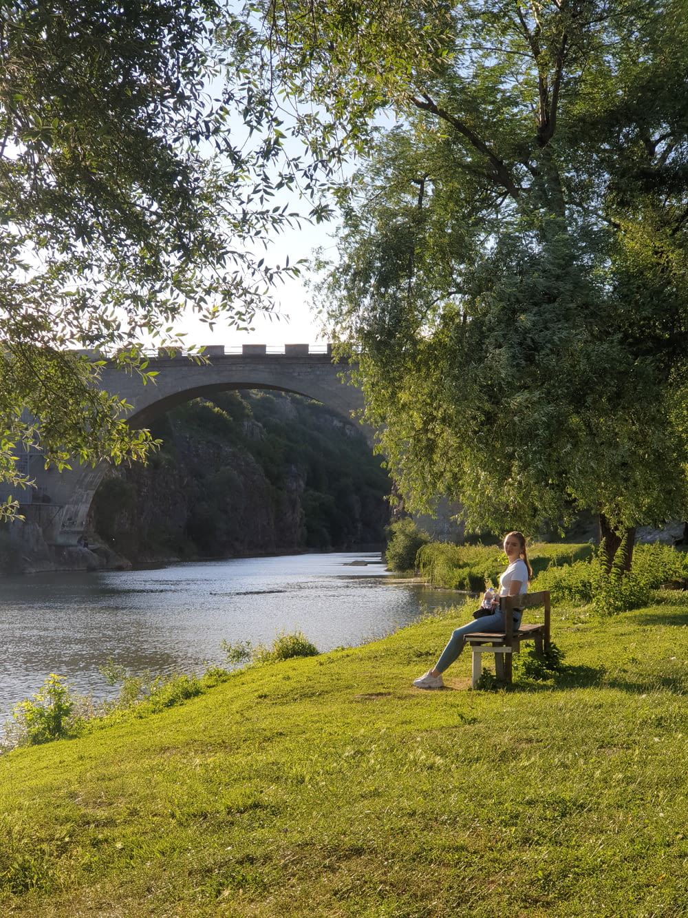 man and woman sitting on green grass near river during daytime