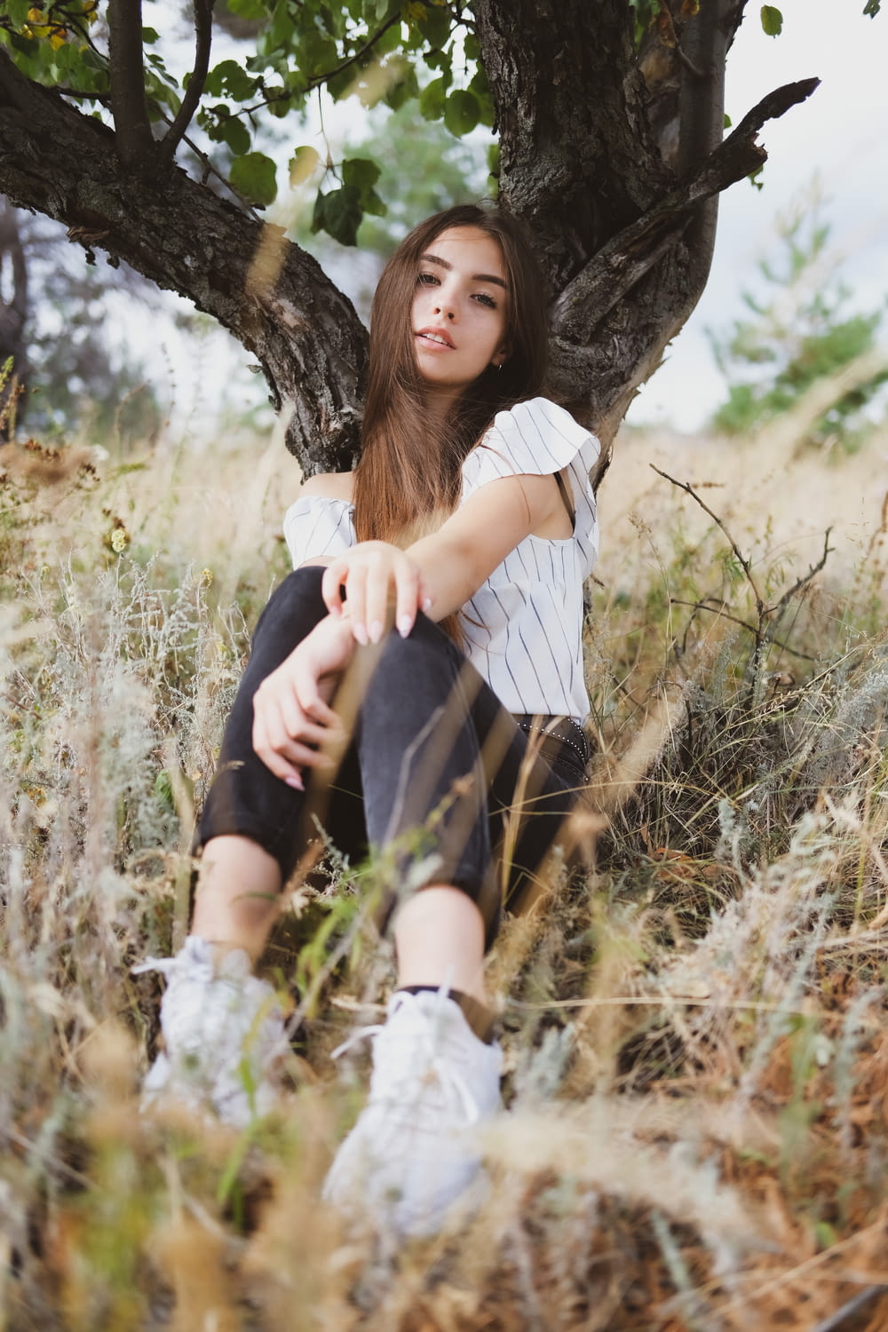 woman in white shirt and black skirt sitting on tree trunk