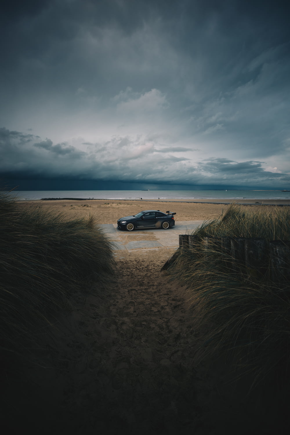 a car is parked in the sand on a cloudy day