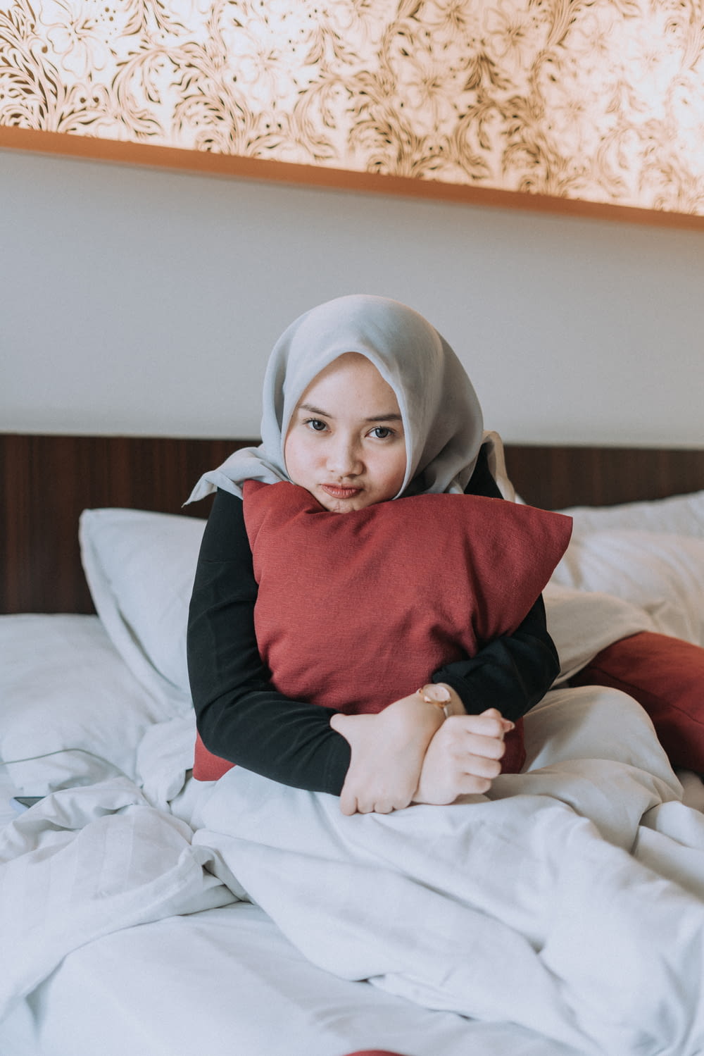 baby in red and black long sleeve shirt and white hijab sitting on bed