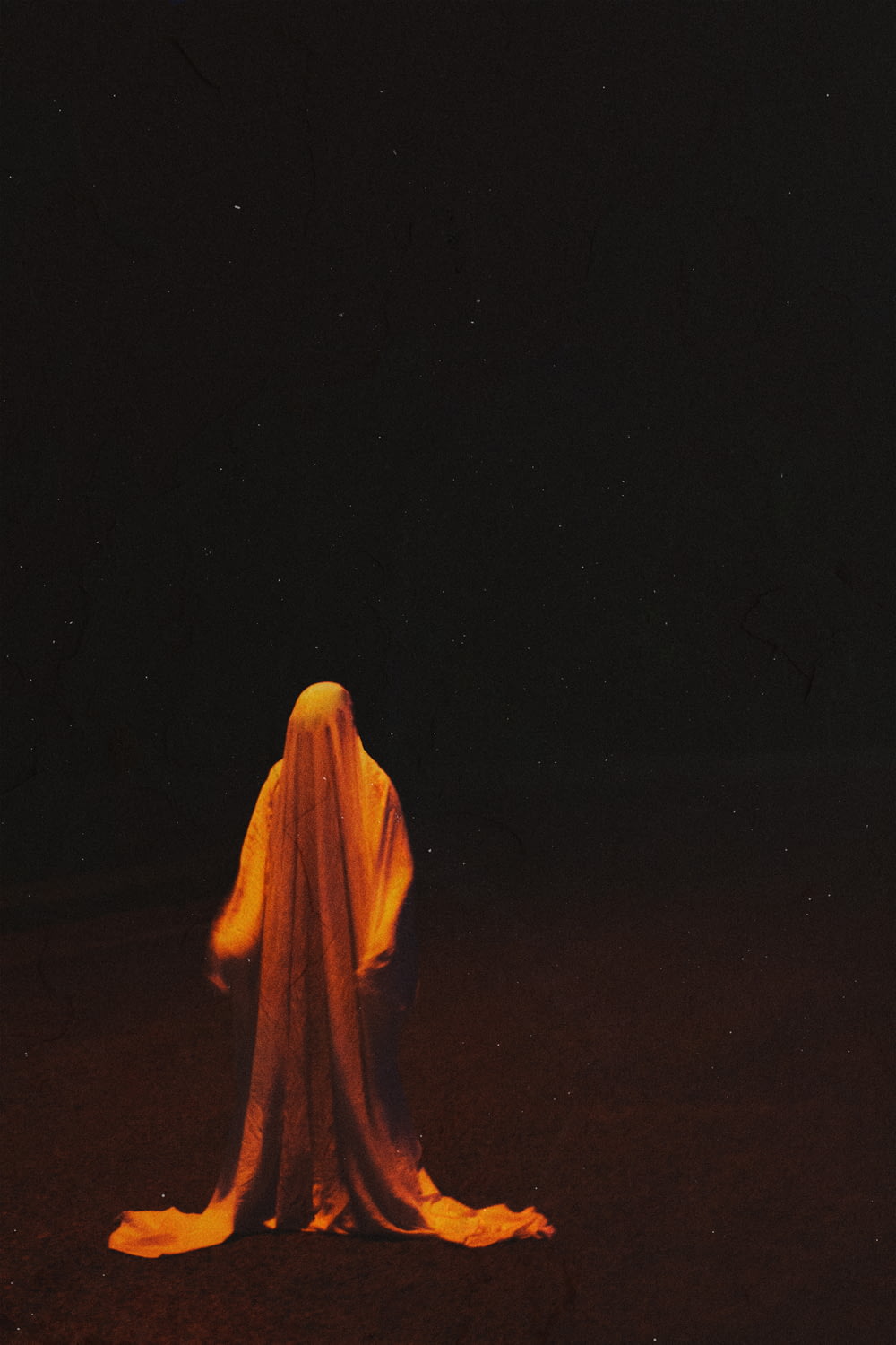 pessoa em hijab amarelo em pé no campo marrom durante a noite