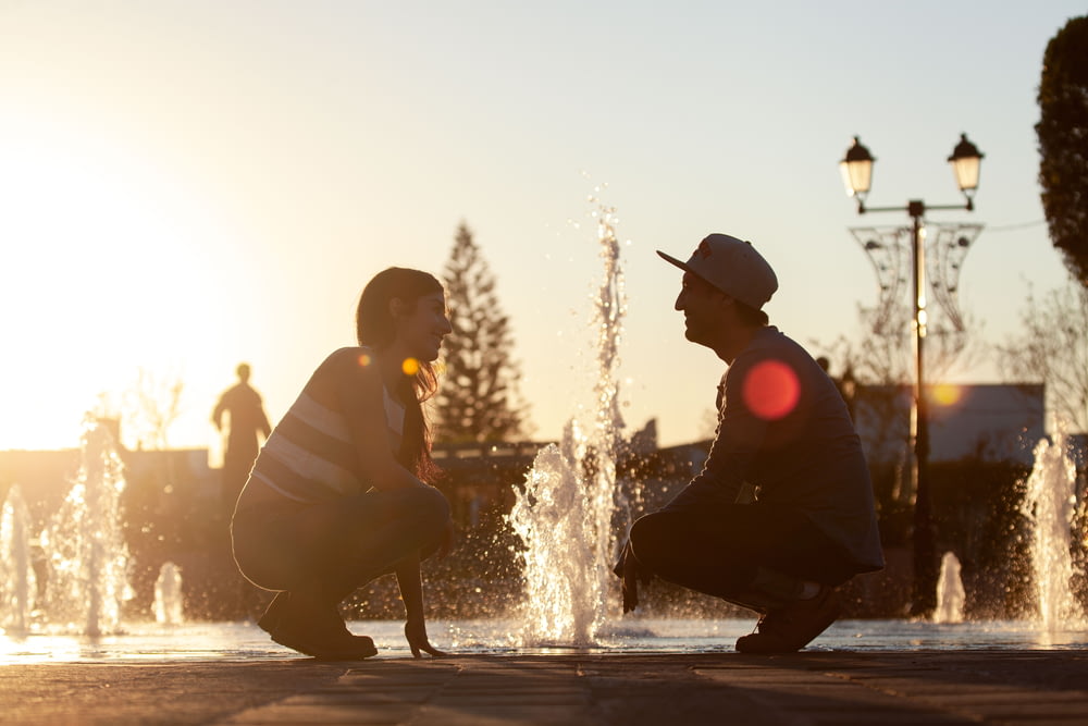 man and woman sitting on water fountain during daytime