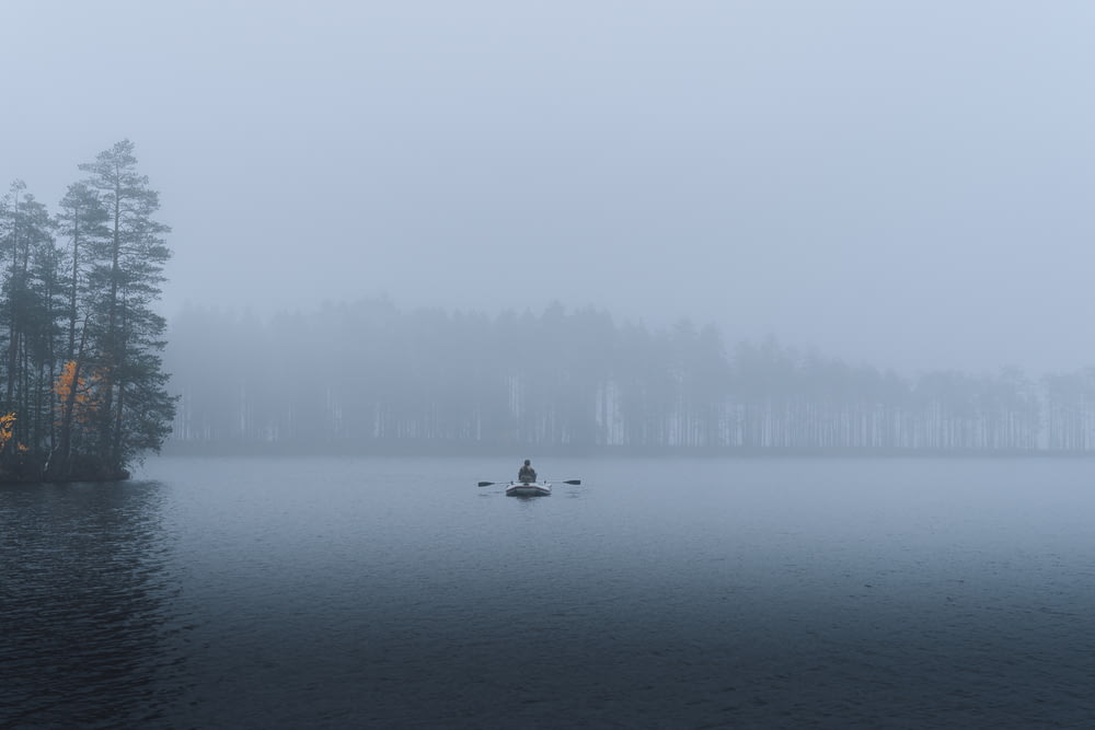 person riding on boat on lake during foggy weather