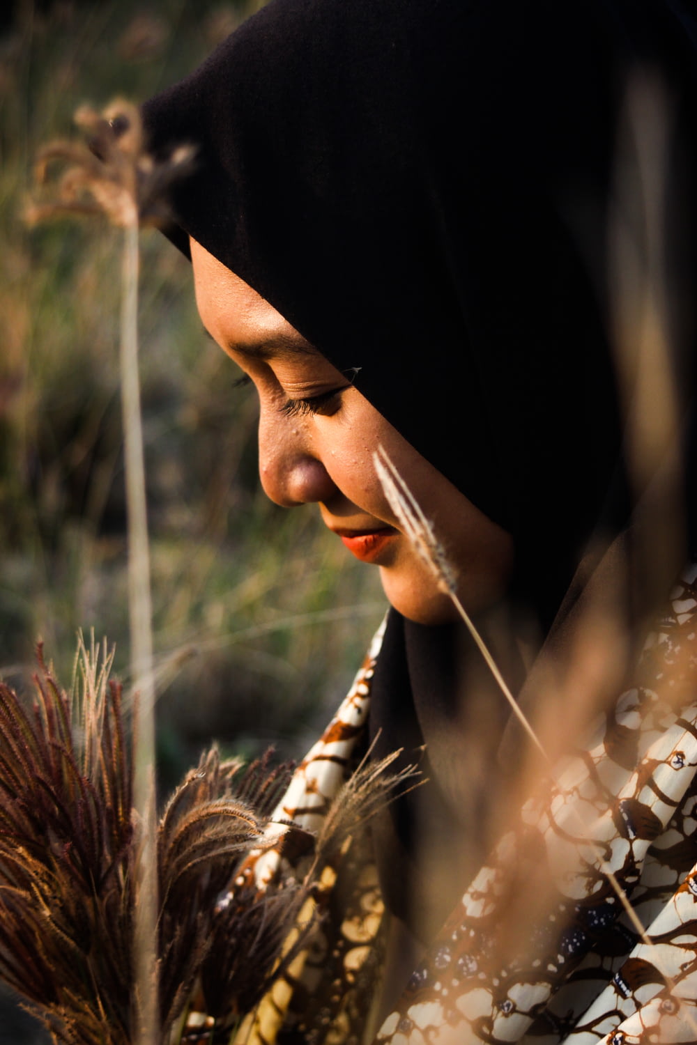 woman in black hijab holding brown wheat
