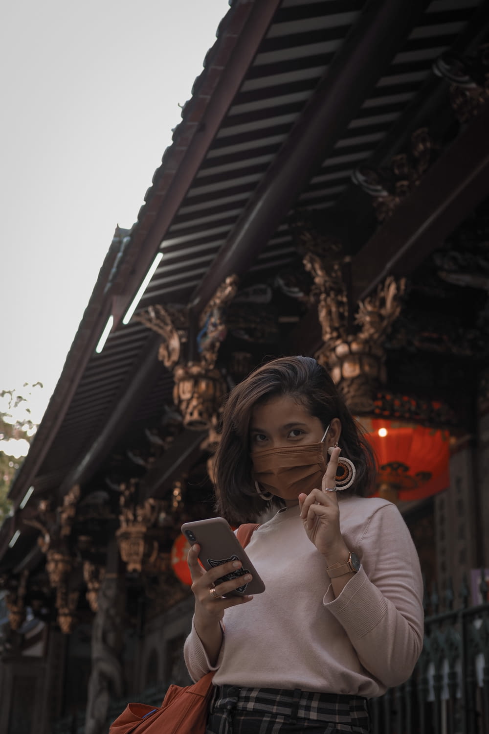 woman in beige long sleeve shirt holding smartphone
