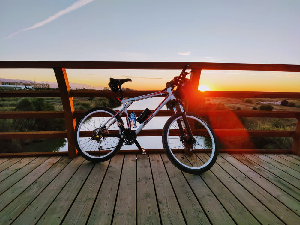 black and red hardtail mountain bike on brown wooden dock during sunset