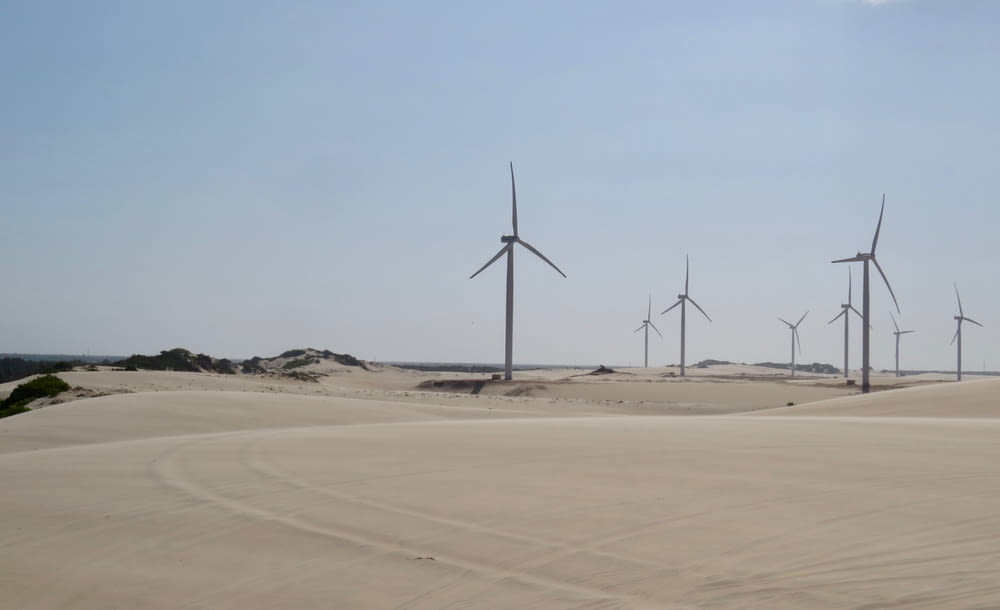 wind turbines on brown sand under gray sky