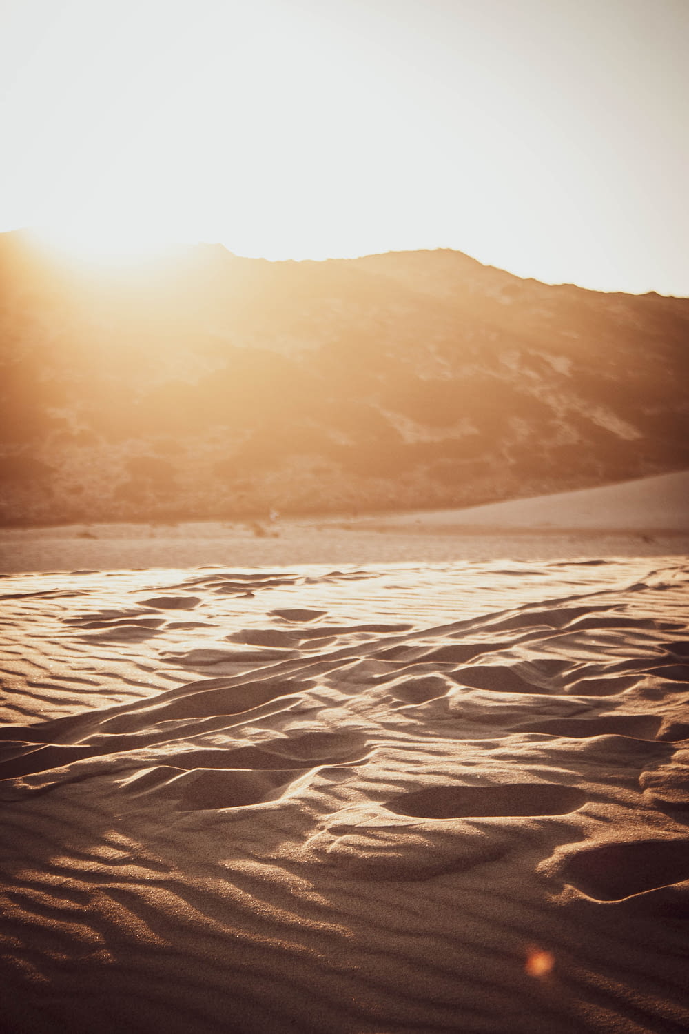 areia branca perto do corpo de água durante o pôr do sol