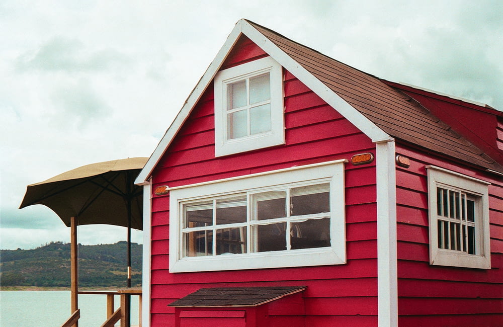 casa de madeira vermelha e branca sob nuvens brancas durante o dia