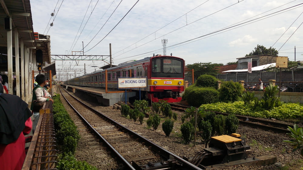 red and yellow train on rail tracks during daytime