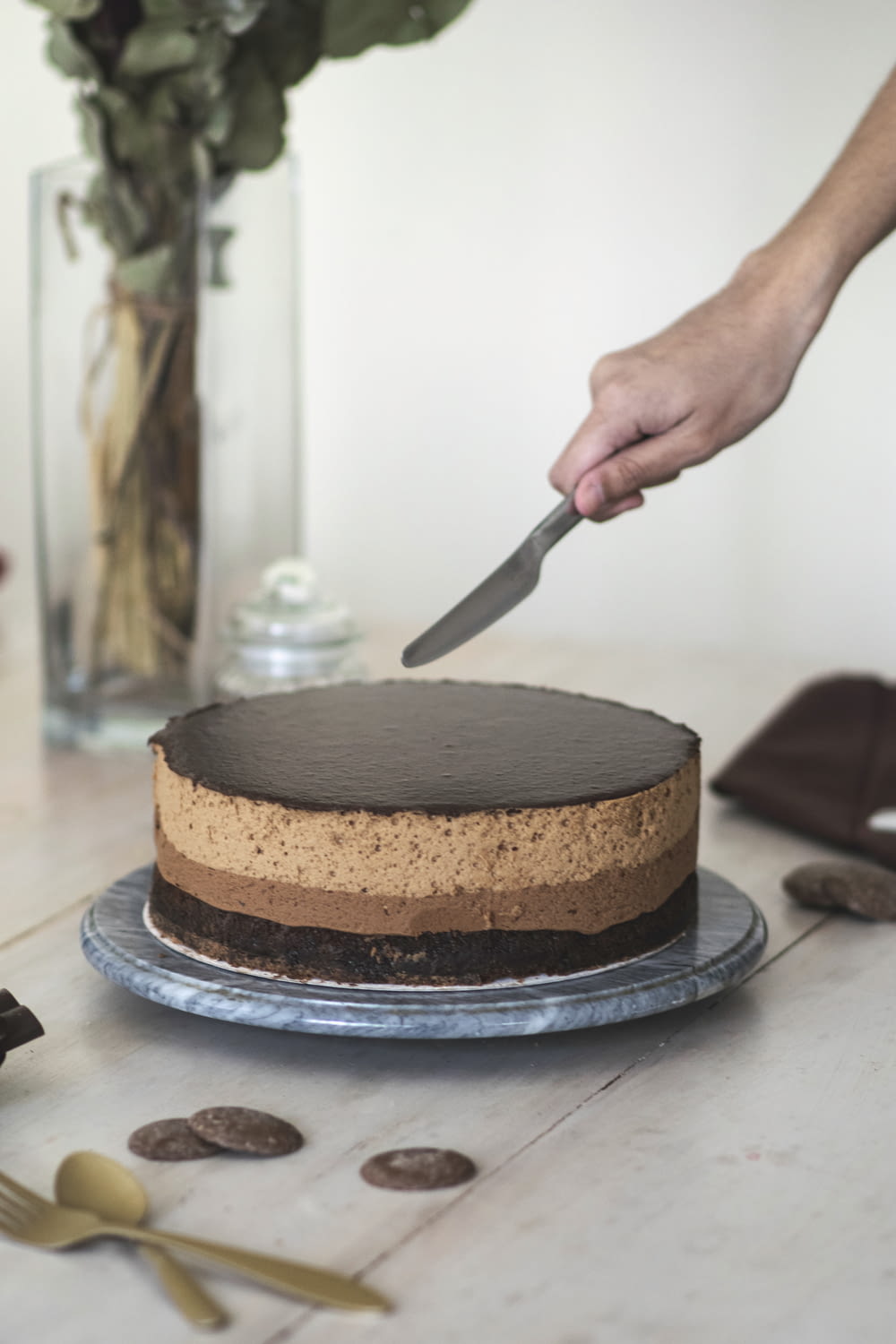 person slicing chocolate cake on black ceramic plate