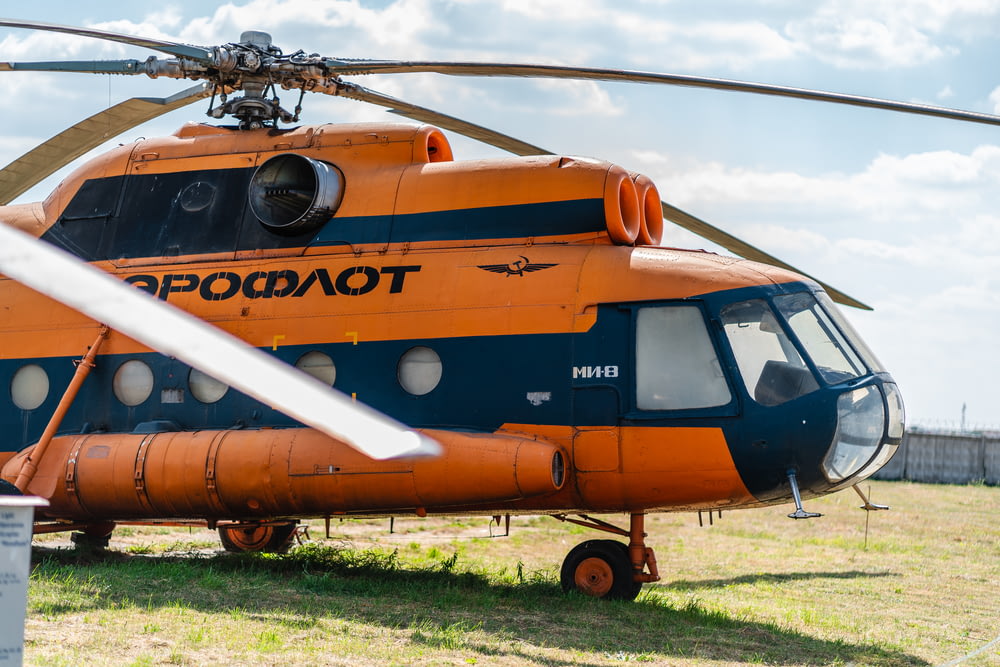 orange and white helicopter on green grass field during daytime